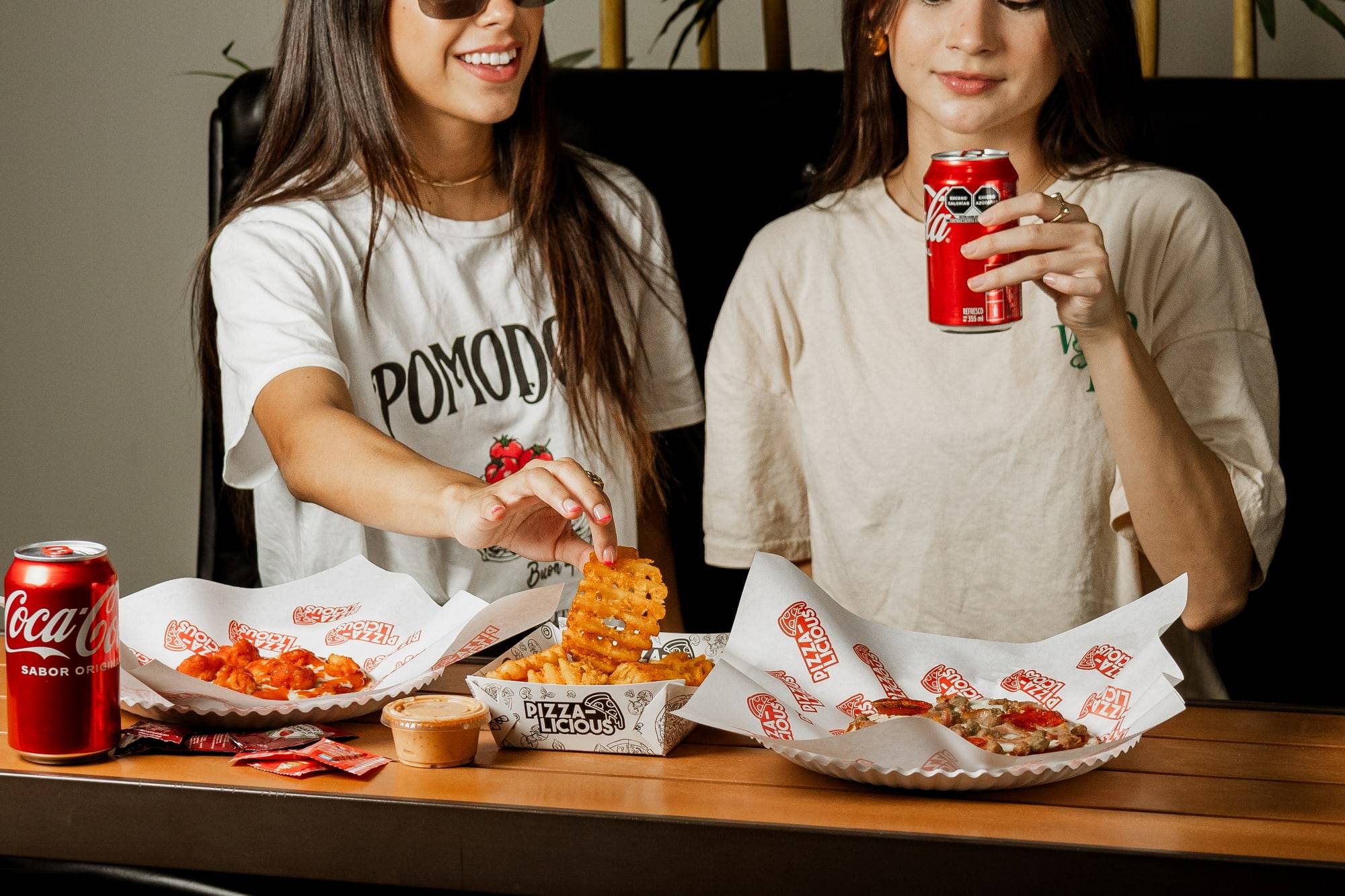 Dos personas compartiendo pizza y papas en una mesa de Pizzalicious en el Mercado Barrio Antiguo