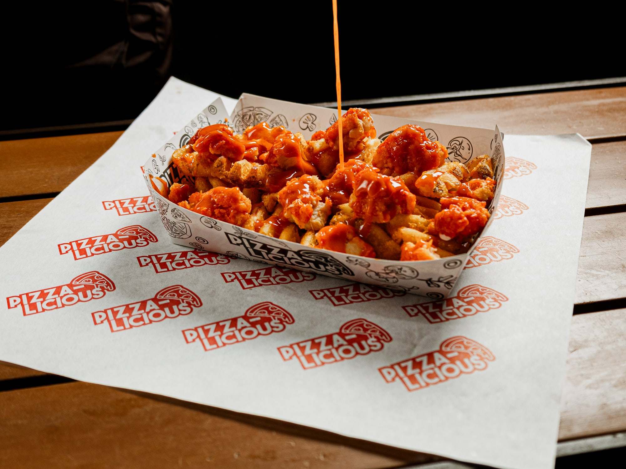 Salsa búfalo cayendo sobre las papas calientes con boneless de Pizzalicious