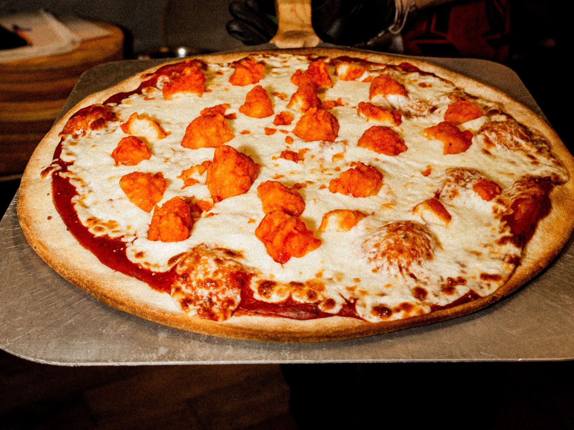 Pizza Boneless de Pizzalicious recién salida del horno sobre la pala de madera